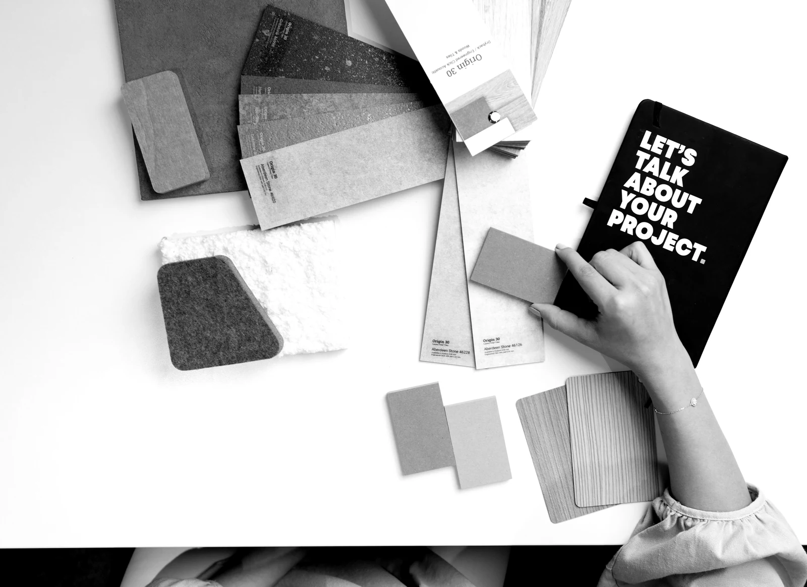 A person holding an orange material sample over a white desk with design swatches. Photograph accompanying Velaharra’s creative direction brief guide.